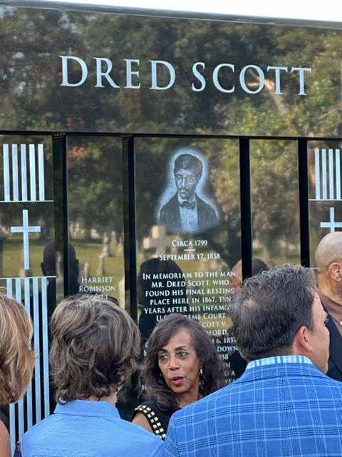 The 165th anniversary of the death of Dred Scott, is commemorated by his great-great granddaughter, Lynne M. Jackson, leading a ceremony dedicating a new, fitting, nine-foot-tall, black granite cemetery monument in Calvary Cemetery to honor this most well-known male of all freedom suits plaintiffs, who was originally buried there in an unmarked grave in 1867.